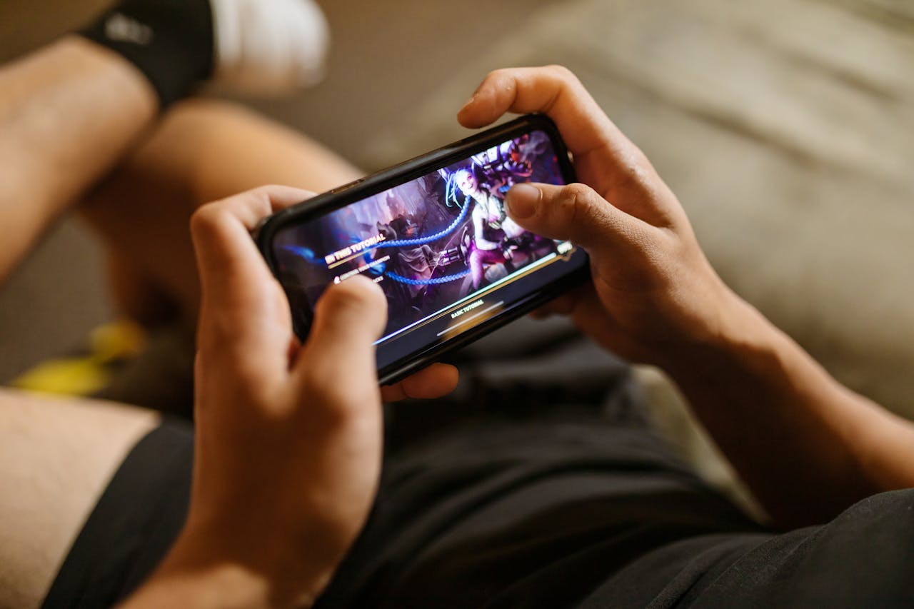 services-04 A person playing a mobile video game on a smartphone, focusing on gaming and technology lifestyle.